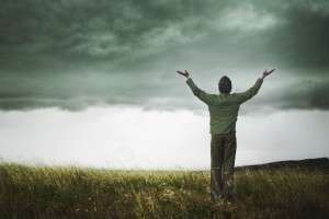 man lifting hands to sky during a storm